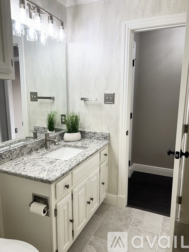 A bathroom with a marble countertop and a white sink.