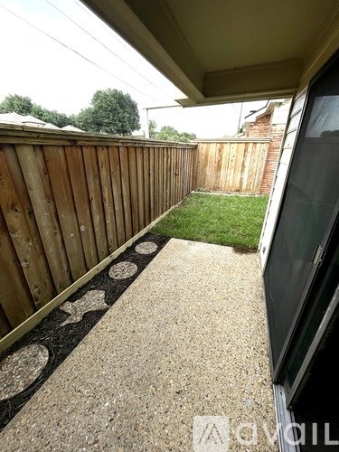 A wooden fence with a concrete pathway and a black and white patterned rug.