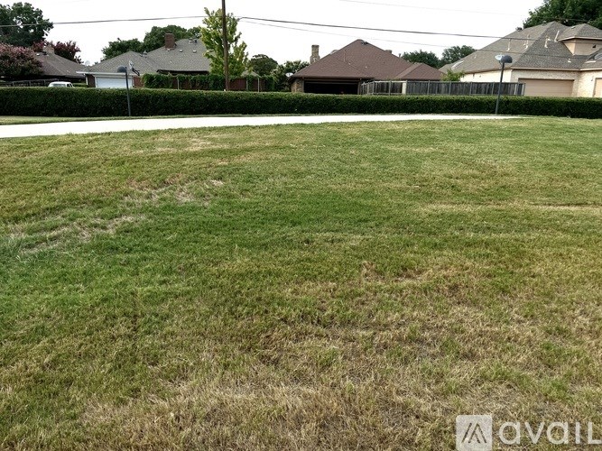 A grassy field with a few houses in the background.