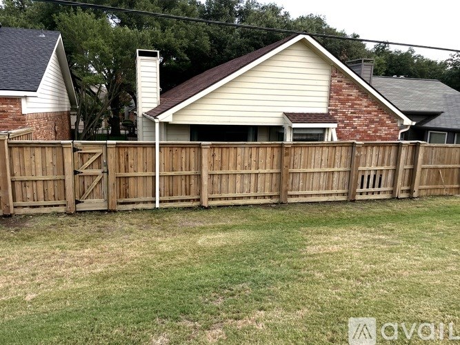 A backyard with a wooden fence and a house in the background.