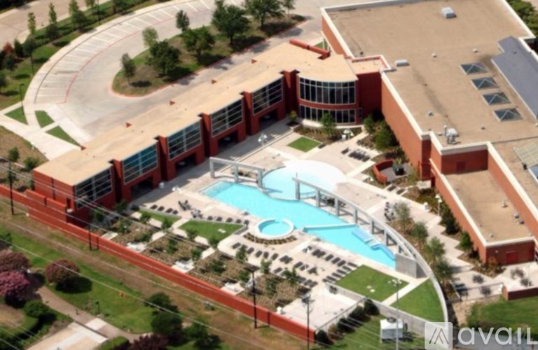 An aerial view of a red building with a swimming pool in front.