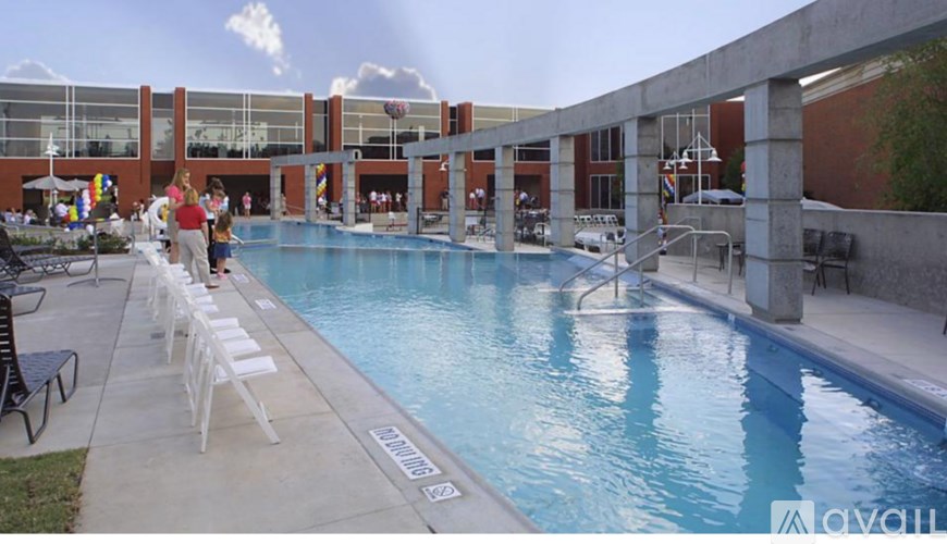 A pool with people around it and a building in the background.