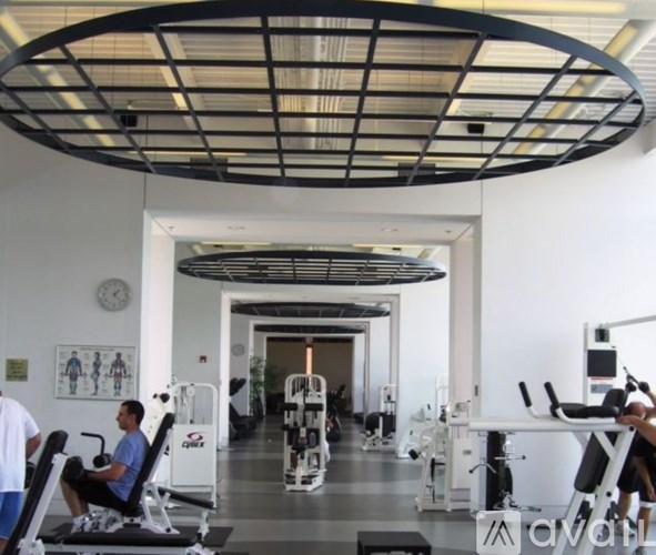 A gym with people working out and a clock on the wall.