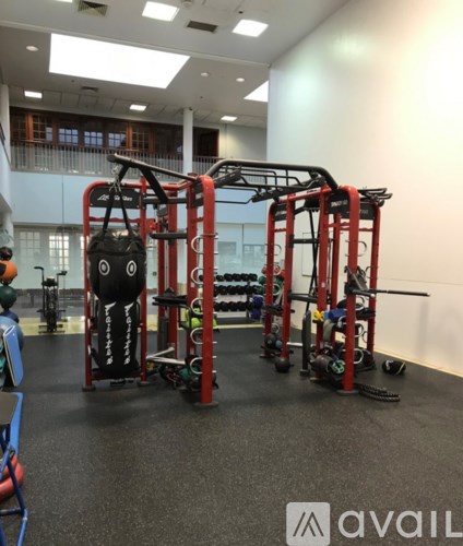 A gym with a red weight machine and a black bag hanging on it.