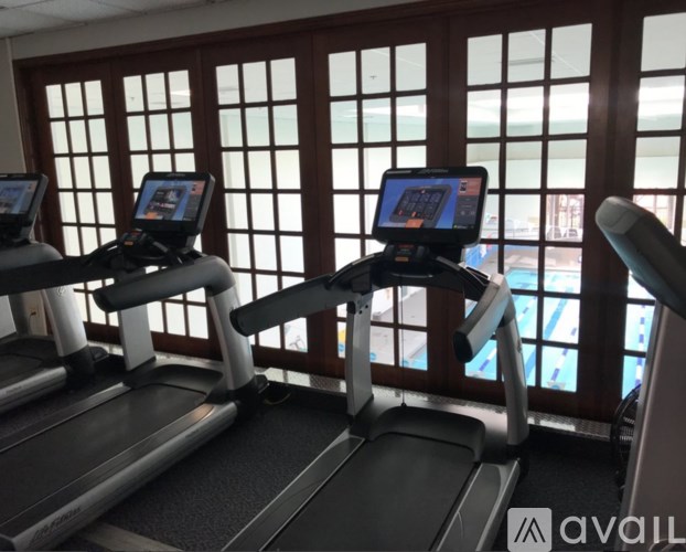 Two treadmills are available for use in a room with a view of a pool through the windows.
