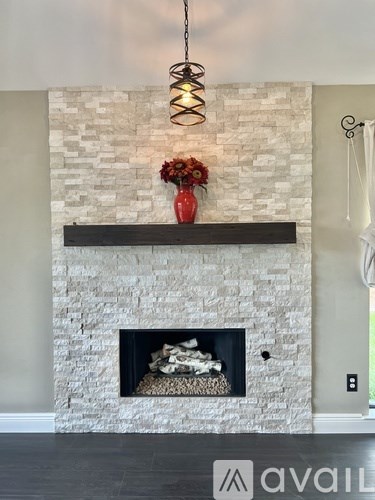 A fireplace with a white brick wall and a red vase on top.