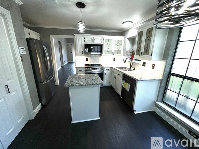 A kitchen with a granite island and stainless steel appliances.