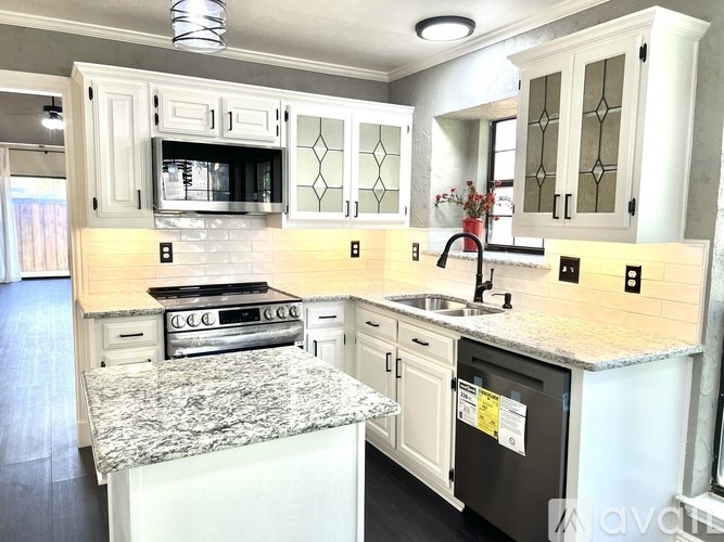A kitchen with white cabinets and a granite countertop.