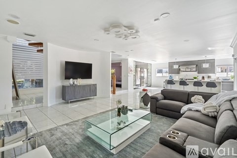 A modern living room with a glass coffee table and grey sofa.