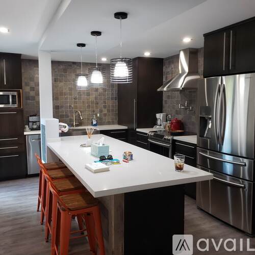 A modern kitchen with a white island and stainless steel appliances.