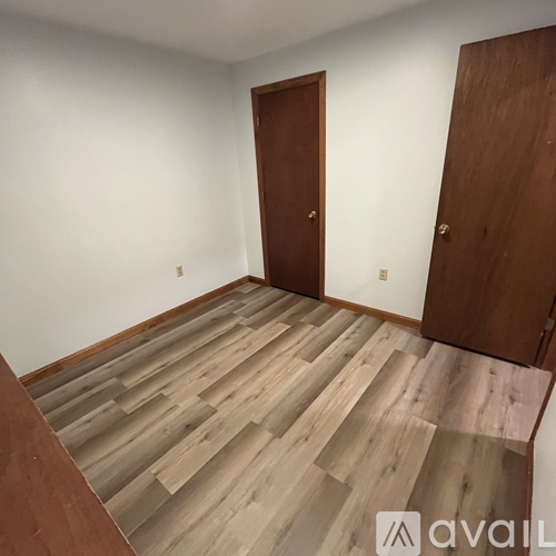 A room with wooden flooring and two doors.