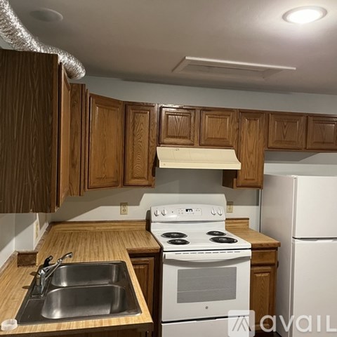 A kitchen with a white stove and wooden cabinets.
