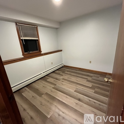 A room with wooden flooring and a window with blinds.