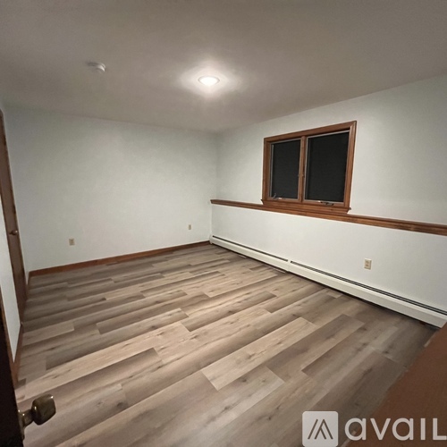 A room with wooden flooring and a window with closed blinds.