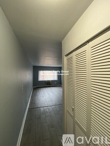 A hallway with a closed door and a window letting in light.