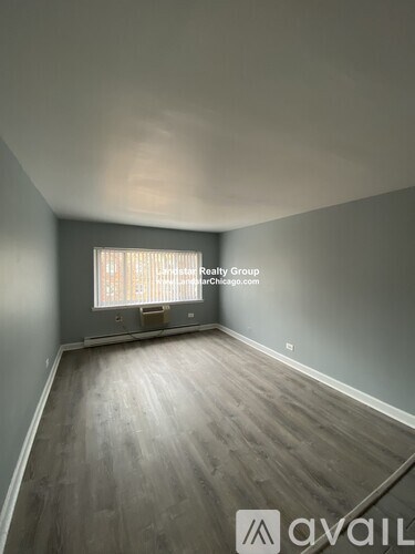A room with wooden flooring and a window with blinds.