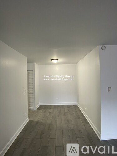 A room with a wooden floor and white walls, with a logo and text for Landstar Realty Group and their website.