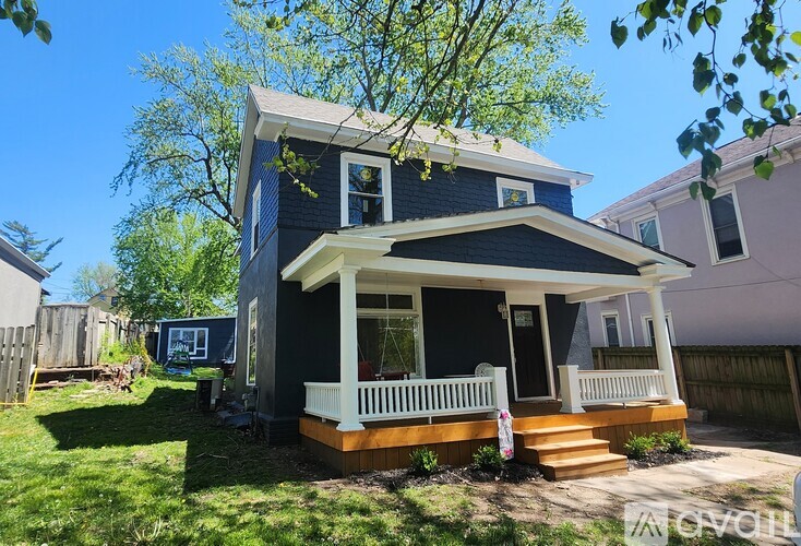 A blue house with a white porch and a white picket fence.