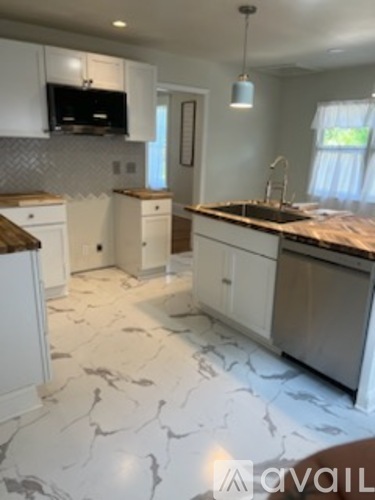 A kitchen with white cabinets and a marble floor.