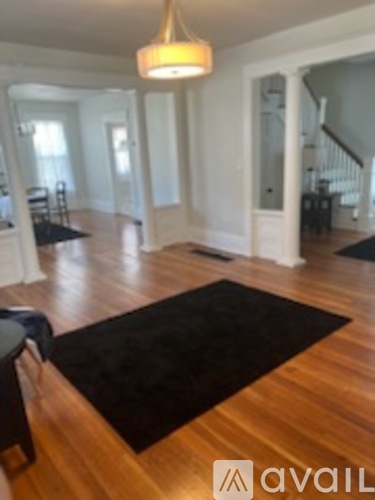 A living room with a black rug on the wooden floor.