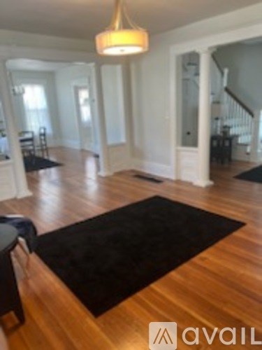 A living room with a black rug on the wooden floor.