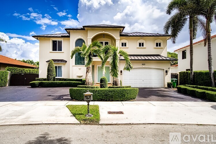 A large house with a driveway and a palm tree in front.
