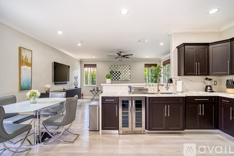 A modern kitchen with dark brown cabinets and a white dining table.