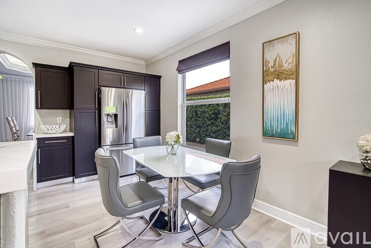 A dining room with a glass table and grey chairs.