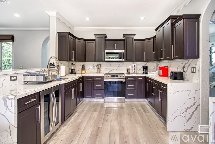 A kitchen with dark brown cabinets and a white marble countertop.