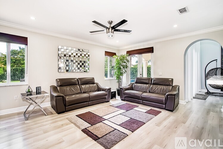 A living room with two brown leather couches and a rug.