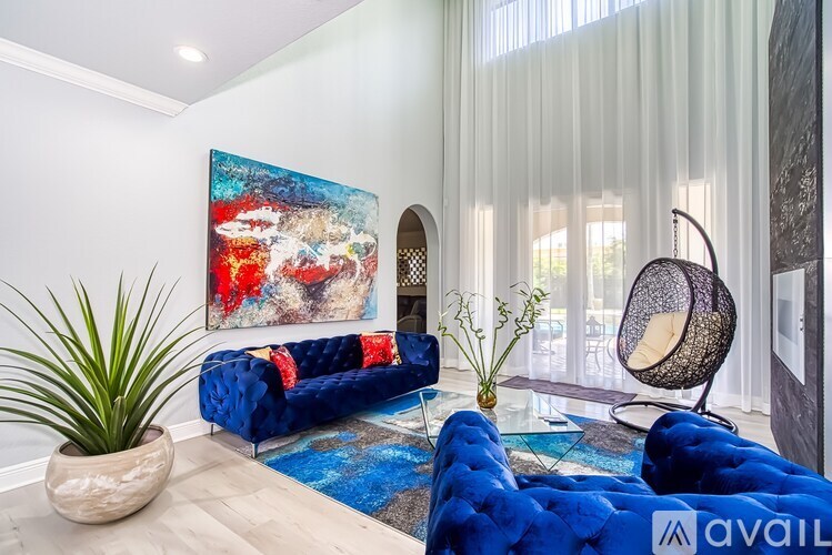 A blue couch sits in a living room with a large painting on the wall.
