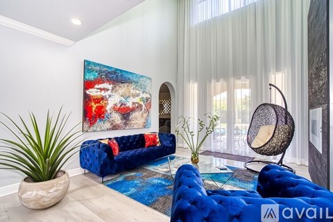A blue couch sits in a living room with a large painting on the wall.