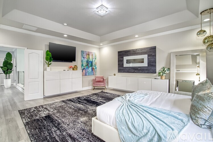 A bedroom with a large bed and a television on the wall.