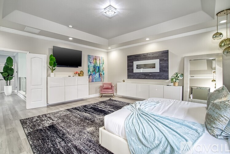 A bedroom with a large bed and a television on the wall.