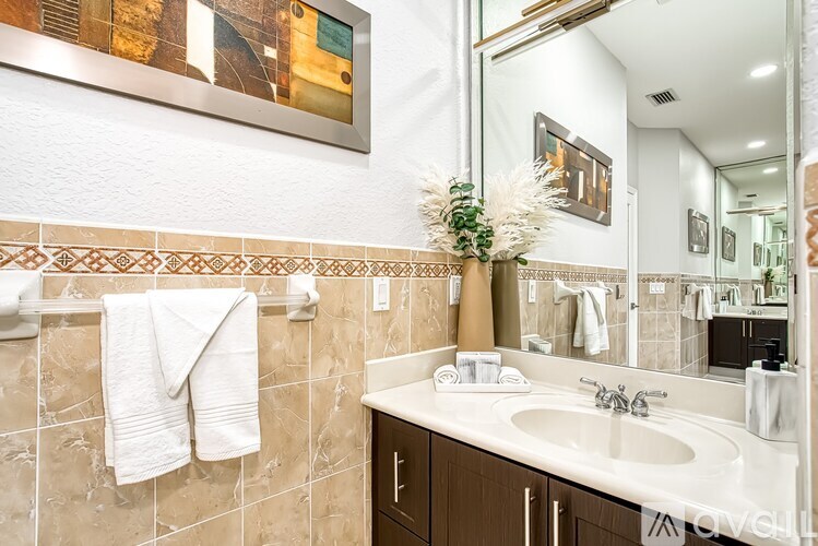 A bathroom with a white sink and brown cabinets.