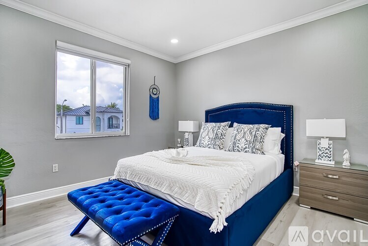 A bedroom with a blue bed and white bedding.
