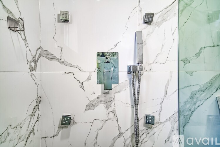 A shower area with a glass door and a marble wall.