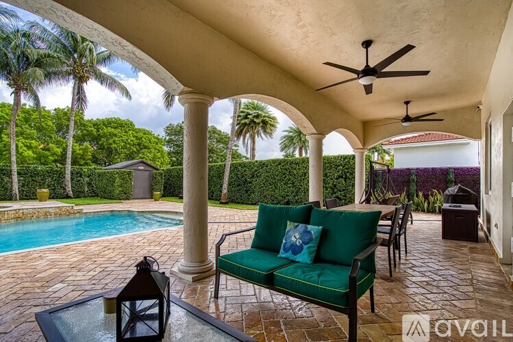 A patio with a green couch and a pool in the background.