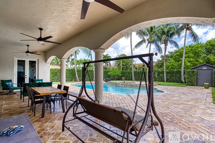 A patio with a table, chairs and a fan.