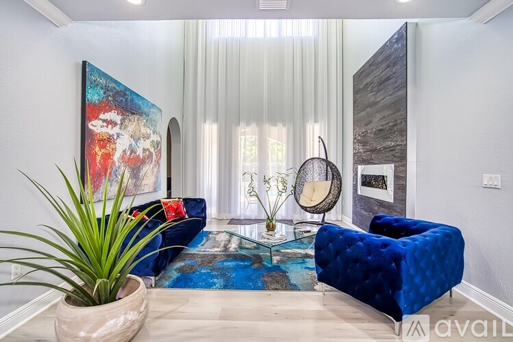 A living room with a blue couch and a large painting on the wall.