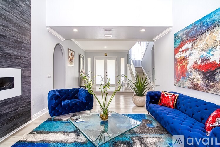 A living room with a blue couch and a glass coffee table.