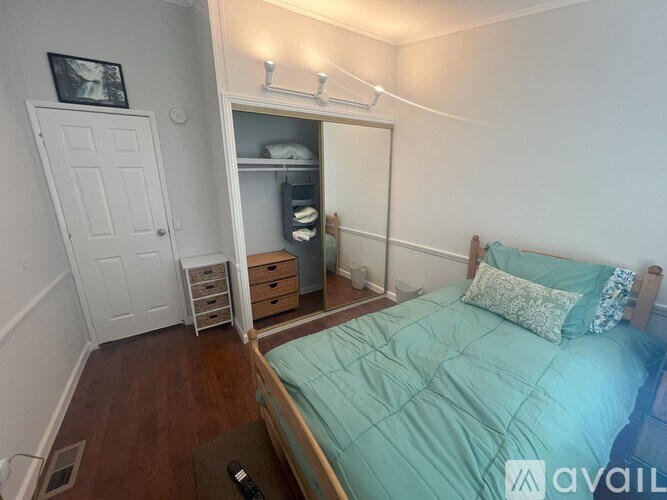 A bedroom with a bed, nightstand, and a small closet.