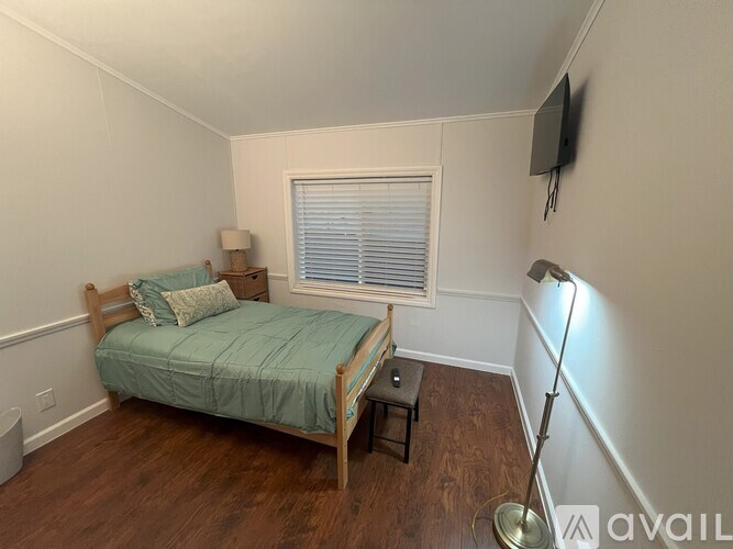 A bedroom with a bed, nightstand, and window.