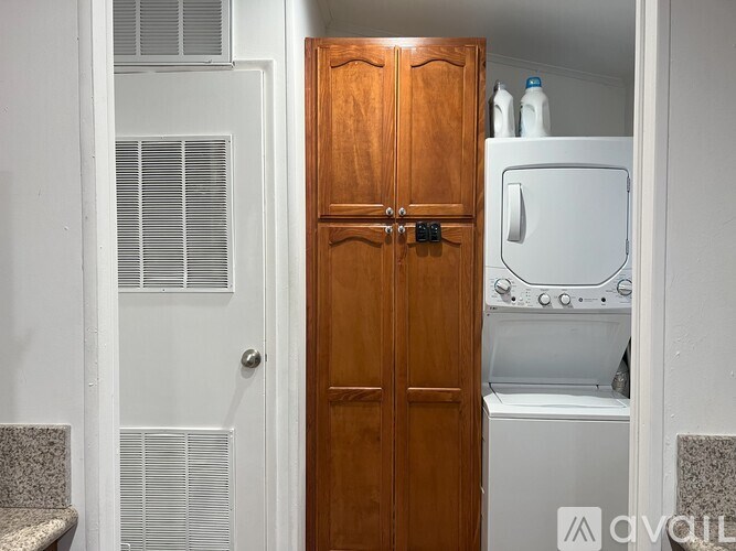 A wooden door opens to a small laundry room with a washer and dryer.