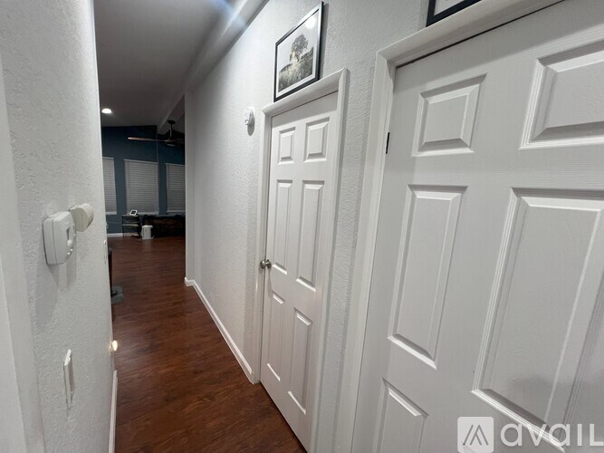 A hallway with white doors and a white wall.