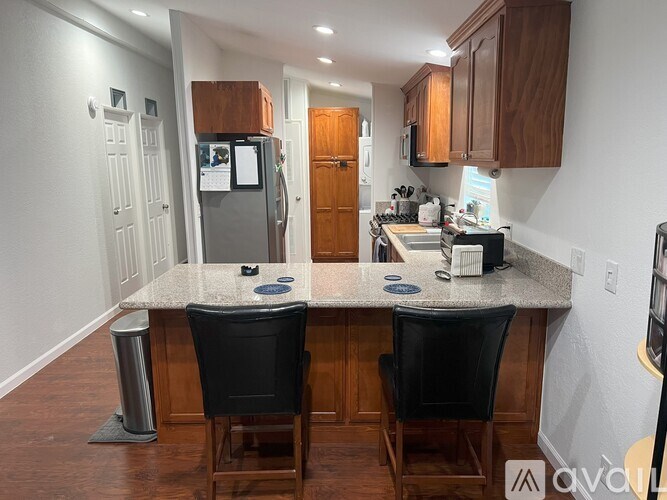 A kitchen with a granite countertop and black chairs.