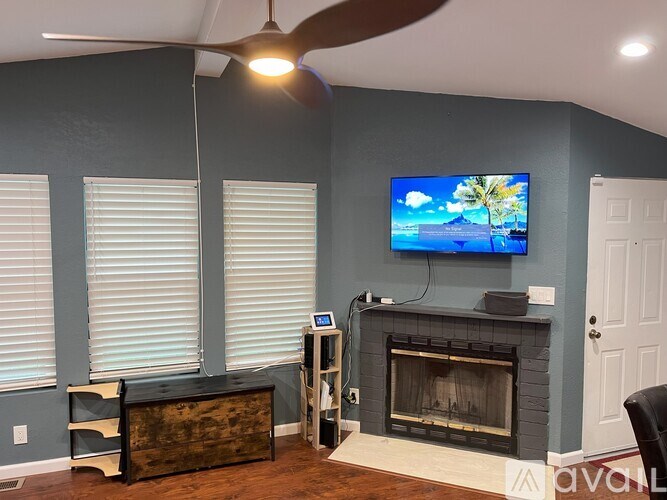 A living room with a television, a fireplace, and a ceiling fan.