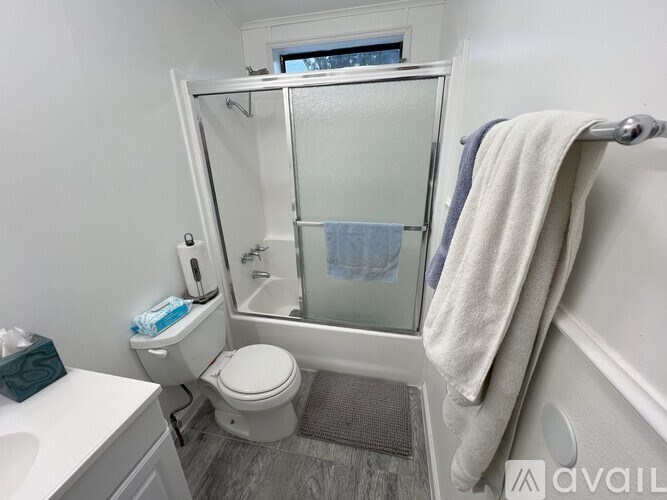 A white toilet with a blue towel and a white sink in a bathroom.