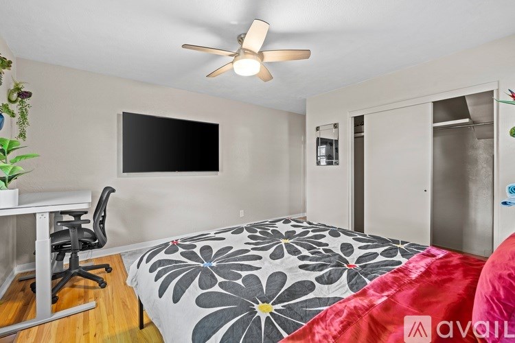 A bedroom with a bed, desk, and a ceiling fan.