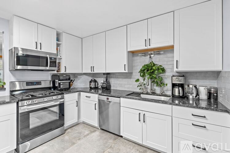 A kitchen with white cabinets and a black countertop.